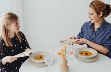 Two women dining with soup at an elegantly set table.