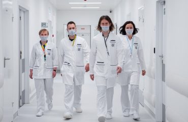Medical team walking confidently in a hospital corridor, wearing face masks and white coats, symbolizing teamwork and healthcare dedication.